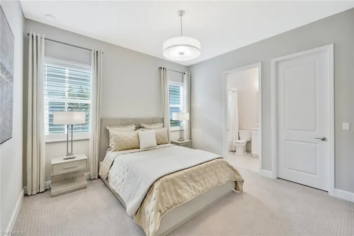 Bedroom featuring light colored carpet and ensuite bath