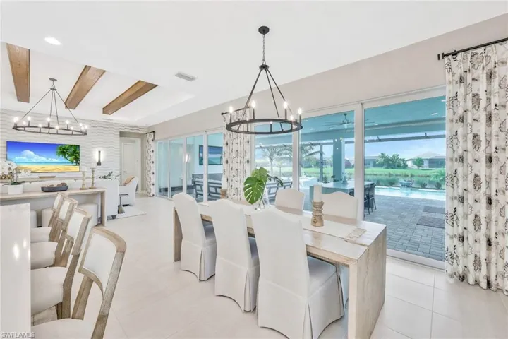 Tiled dining space featuring beamed ceiling and an inviting chandelier