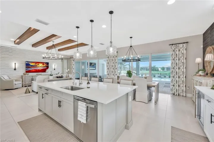 Kitchen featuring dishwasher, sink, decorative light fixtures, and a center island with sink