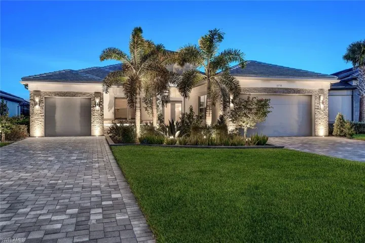 View of front of house featuring a garage and a front lawn with lighting
