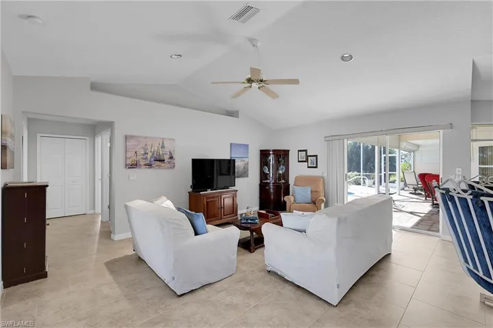 Family room featuring vaulted ceiling, a ceiling fan, display shelf and light tile patterned floors