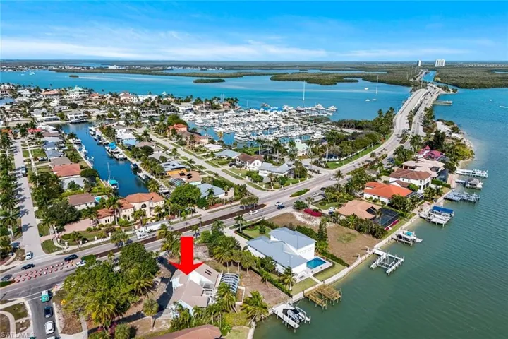 Aerial view of property and surrounding area with a nearby body of water, a marina, and nearby suburban area