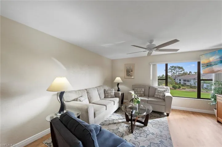 Living area featuring wood-finish flooring, ceiling fan, and large picture window with outdoor landscape scenery