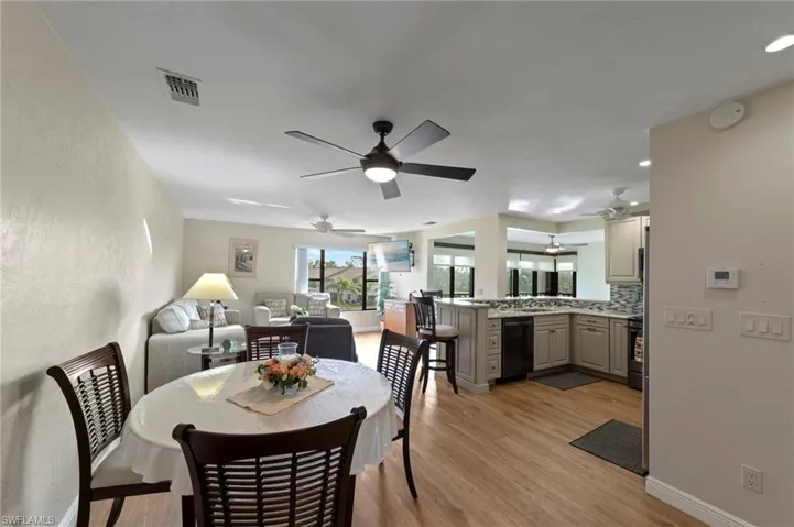 Open concept interior featuring wood-finish flooring, ceiling fans with integrated lighting, kitchen cabinetry, and a peninsula counter