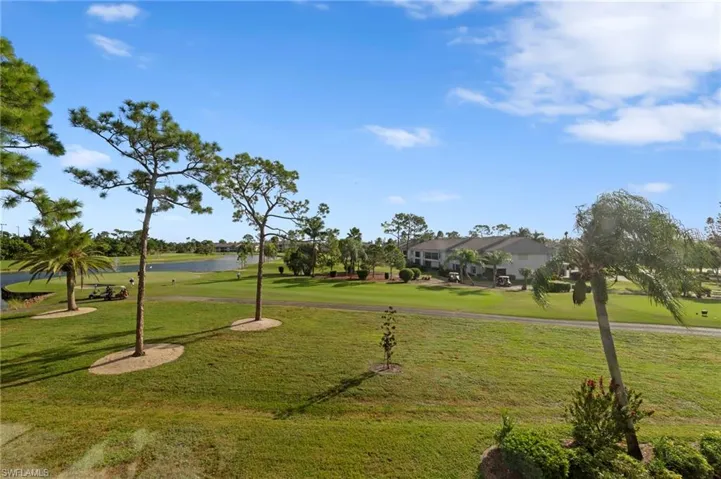 Expansive green space featuring mature landscaping, a pond, and golf course terrain