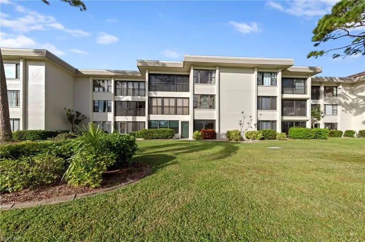 Multi-story exterior featuring light-toned stucco siding, horizontal roofline detailing, and private screened balconies