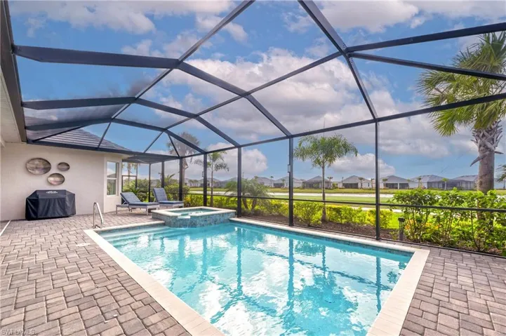 View of pool with an in ground hot tub, a patio, area for grilling, and a lanai
