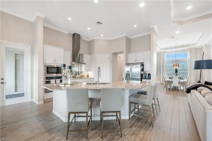 Kitchen with white cabinets, appliances with stainless steel finishes, a large island, and sink