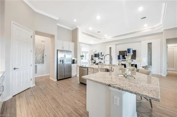 Kitchen featuring sink, stainless steel appliances, a kitchen breakfast bar, a spacious island, and white cabinets