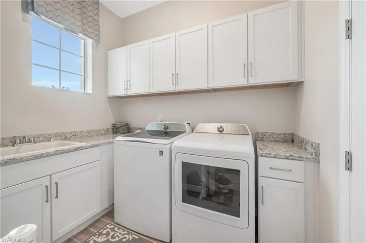 Laundry room with hardwood / wood-style flooring, cabinets, separate washer and dryer, and sink