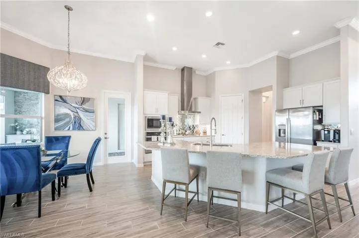 Kitchen with white cabinetry, sink, stainless steel appliances, and a large island