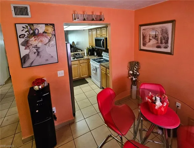 Kitchen featuring light tile patterned flooring, light brown cabinets, and white range with electric stovetop