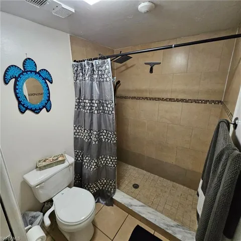 Bathroom with toilet, tile patterned floors, and walk in shower