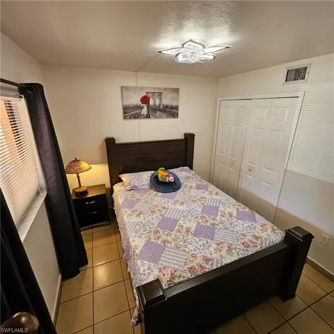 Bedroom with a closet, ceiling fan, and tile patterned flooring