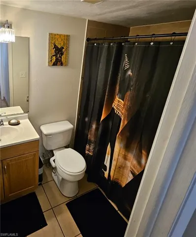 Bathroom with vanity, a textured ceiling, toilet, and tile patterned floors