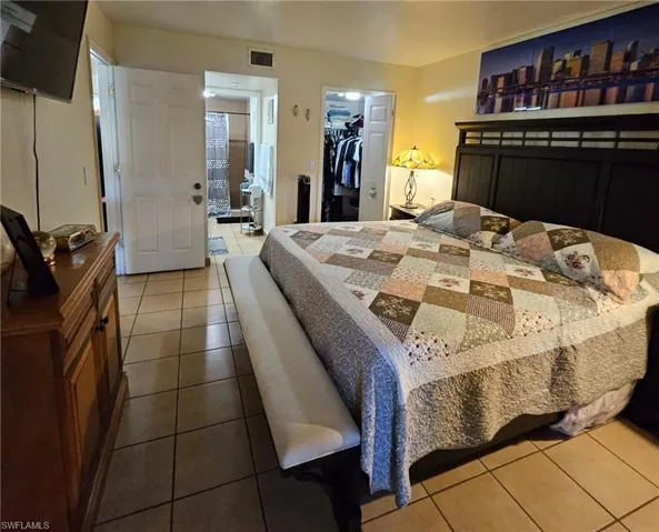 Bedroom with a walk in closet, a closet, and light tile patterned floors