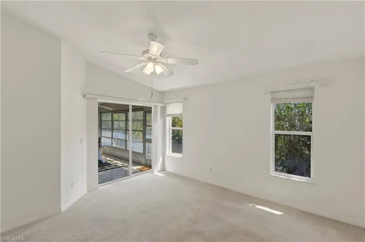 Unfurnished room featuring a ceiling fan, carpet, lofted ceiling, and healthy amount of natural light