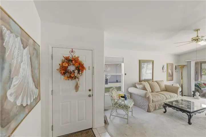 Entryway featuring lofted ceiling, ceiling fan, and light carpet