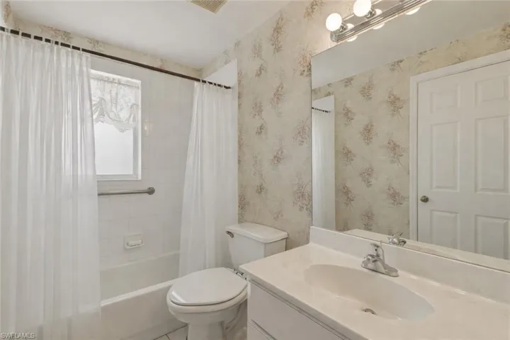 Bathroom featuring vanity and shower / bath combination with curtain