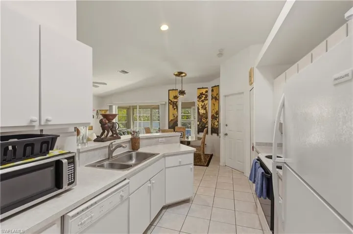 Kitchen with white cabinetry, white appliances, light countertops, hanging light fixtures, and a peninsula