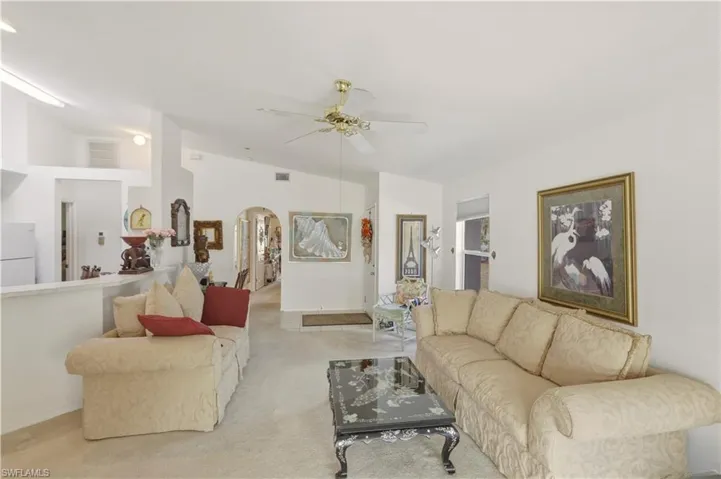 Living area with arched walkways, a ceiling fan, carpet flooring, and lofted ceiling