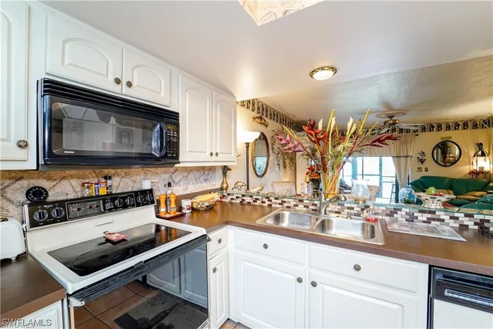 Kitchen with electric range oven, dark countertops, and white cabinetry