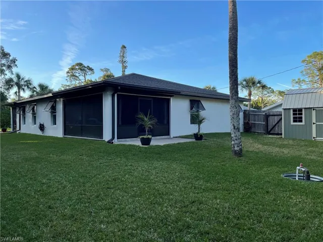 Back of property featuring a lawn, a sunroom, and a shed