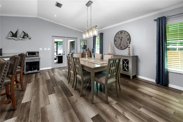Dining area featuring lofted ceiling, crown molding, dark wood-type flooring, and a wealth of natural light