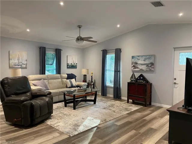 Living room featuring light wood-type flooring, a wealth of natural light, and lofted ceiling