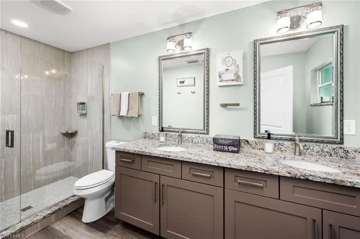 Bathroom with vanity, toilet, an enclosed shower, and hardwood / wood-style flooring