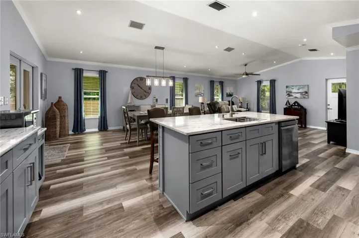 Kitchen with gray cabinets, sink, an island with sink, and plenty of natural light