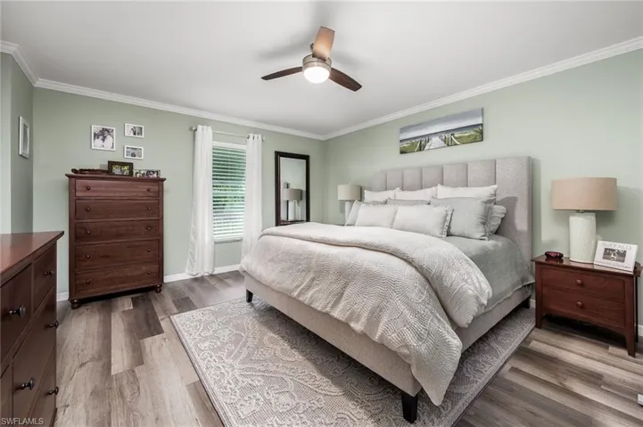 Bedroom with ceiling fan, hardwood / wood-style floors, and crown molding