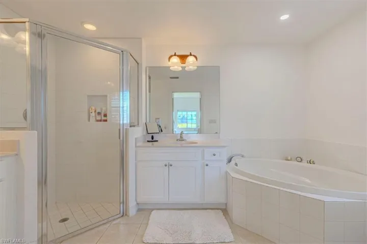 Full bath featuring a shower stall, vanity, a bath, light tile patterned floors, and recessed lighting