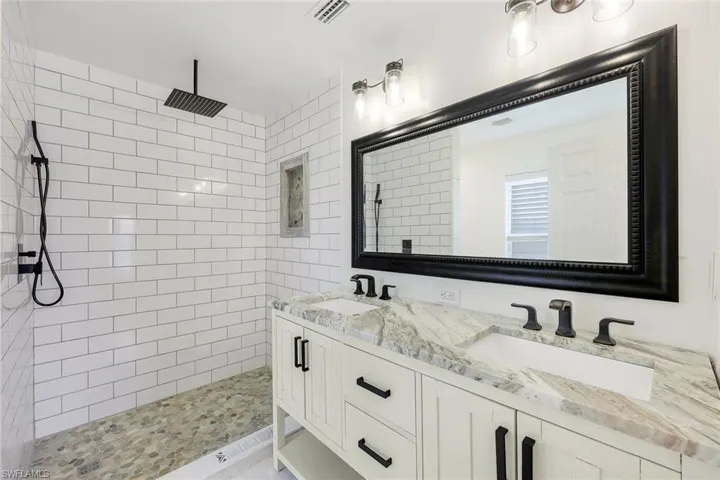 Stunning primary bathroom features dual sinks, subway tile, and rain shower head.