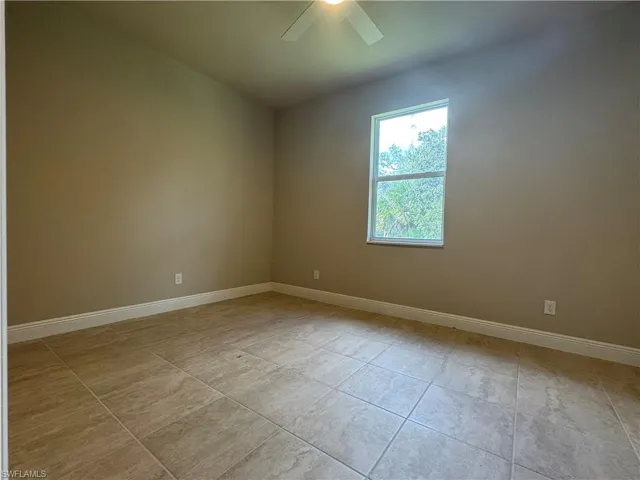 Empty room with ceiling fan and light tile patterned floors