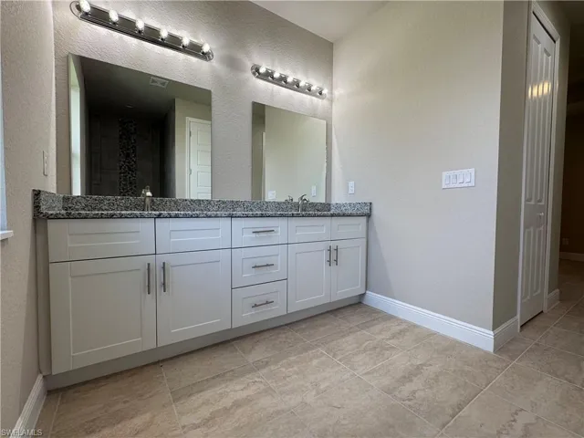 Bathroom featuring vanity, walk in shower, and tile patterned flooring