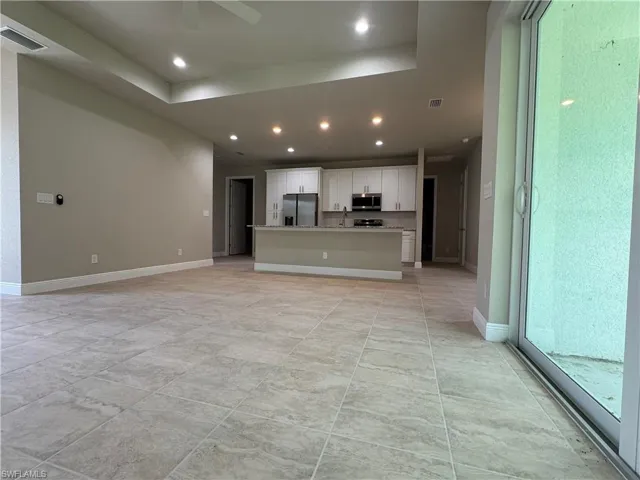 Unfurnished living room with sink and a tray ceiling