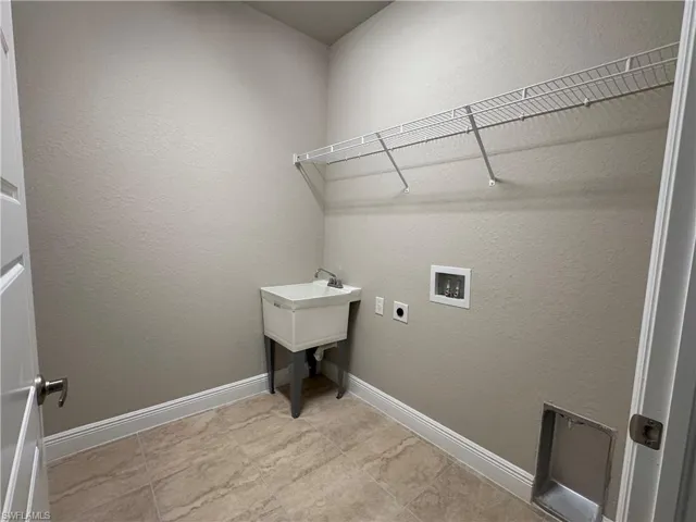 Clothes washing area featuring hookup for an electric dryer, washer hookup, and light tile patterned floors