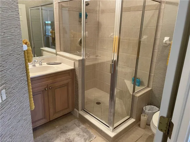 door, vanity, tile patterned floors, and toilet