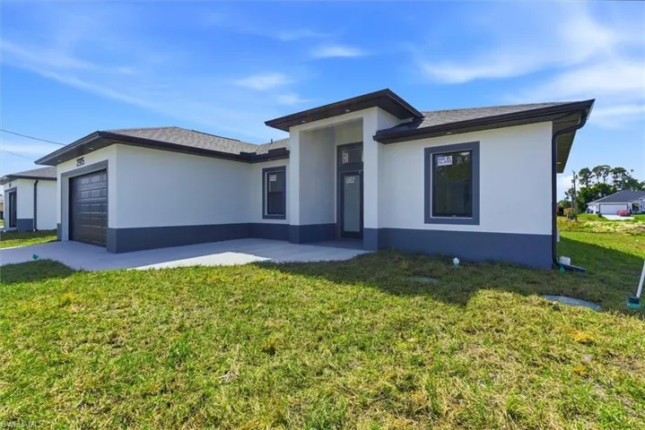 Prairie-style home featuring an attached garage, a front lawn, stucco siding, roof with shingles, and driveway