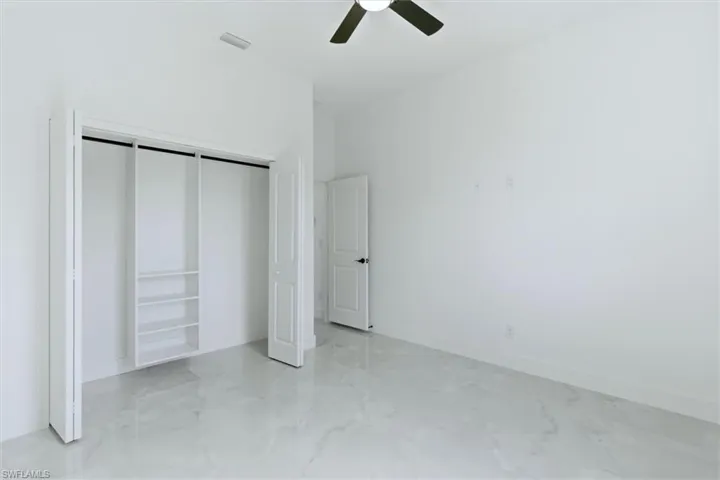 Unfurnished bedroom featuring a closet, a ceiling fan, and light marble finish floors