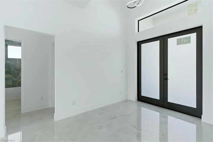 Unfurnished room with french doors, a high ceiling, and light marble finish flooring