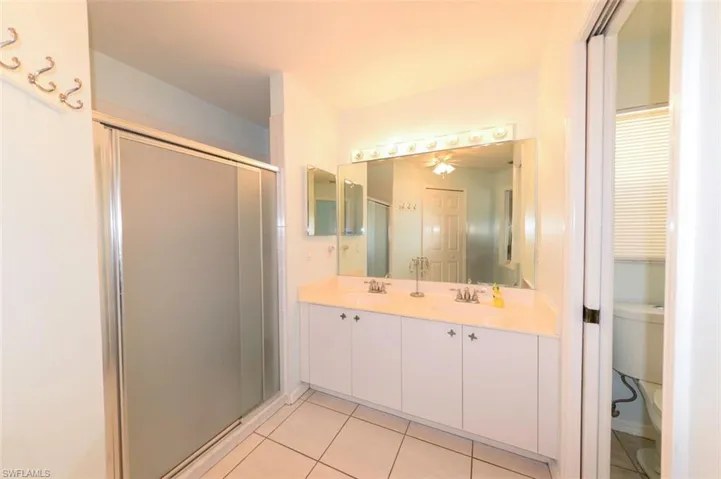 and private master bath featuring double sink vanity, a shower, and private commode area.