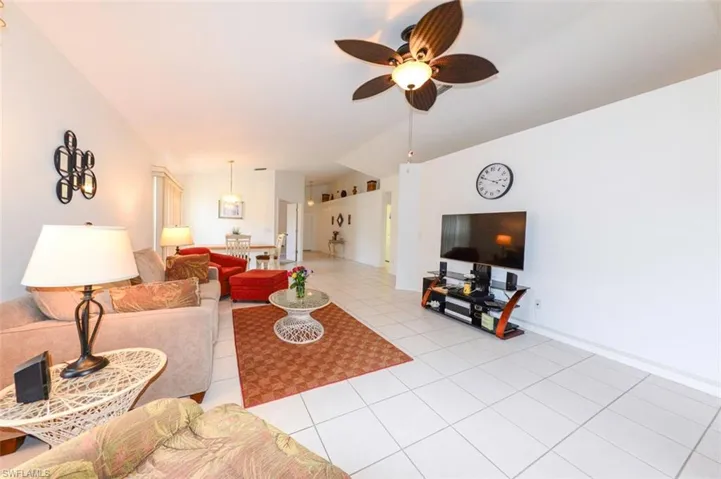 with ceiling fan, light tile patterned floors, and vaulted ceiling and...