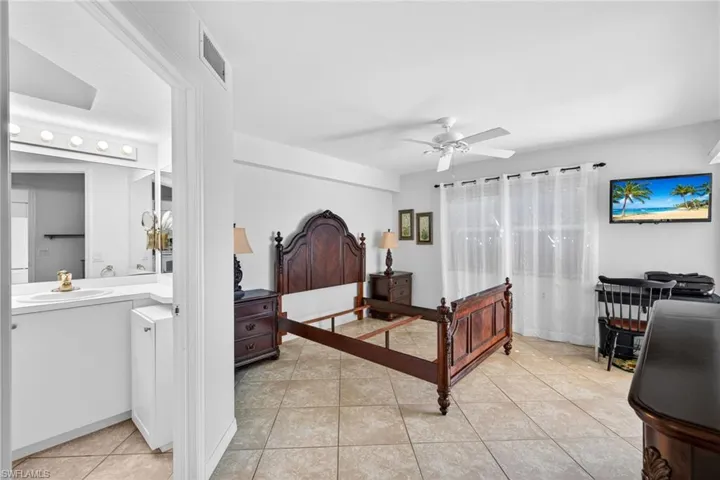 Bedroom featuring a ceiling fan, light tile patterned floors, and connected bathroom