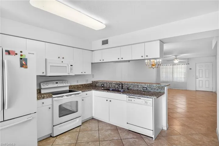 Kitchen featuring white appliances, white cabinets, and ceiling fan