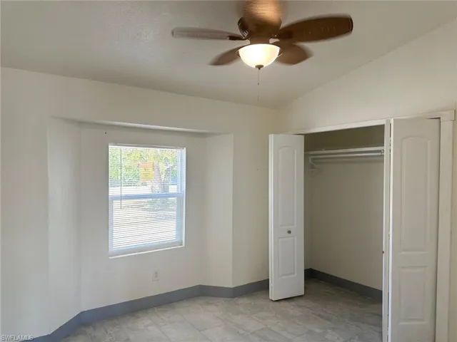 Unfurnished bedroom with a ceiling fan, a closet, and lofted ceiling