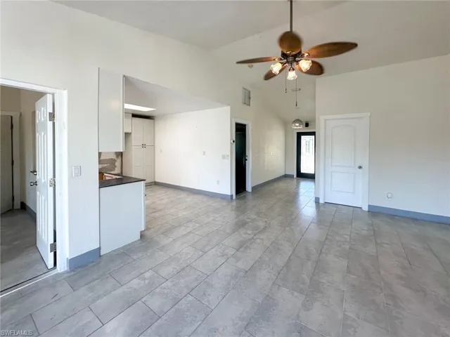 Unfurnished living room with ceiling fan and high vaulted ceiling