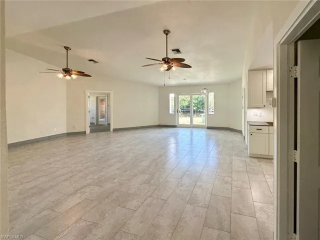 Unfurnished living room featuring ceiling fan and lofted ceiling