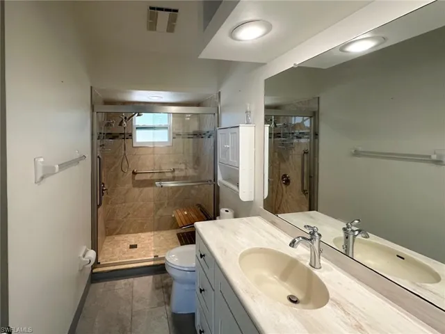 Bathroom with vanity, a stall shower, and dark tile patterned floors